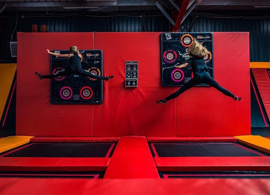 Two girls jumping to reach Freestyle Duo lightpods at trampoline park