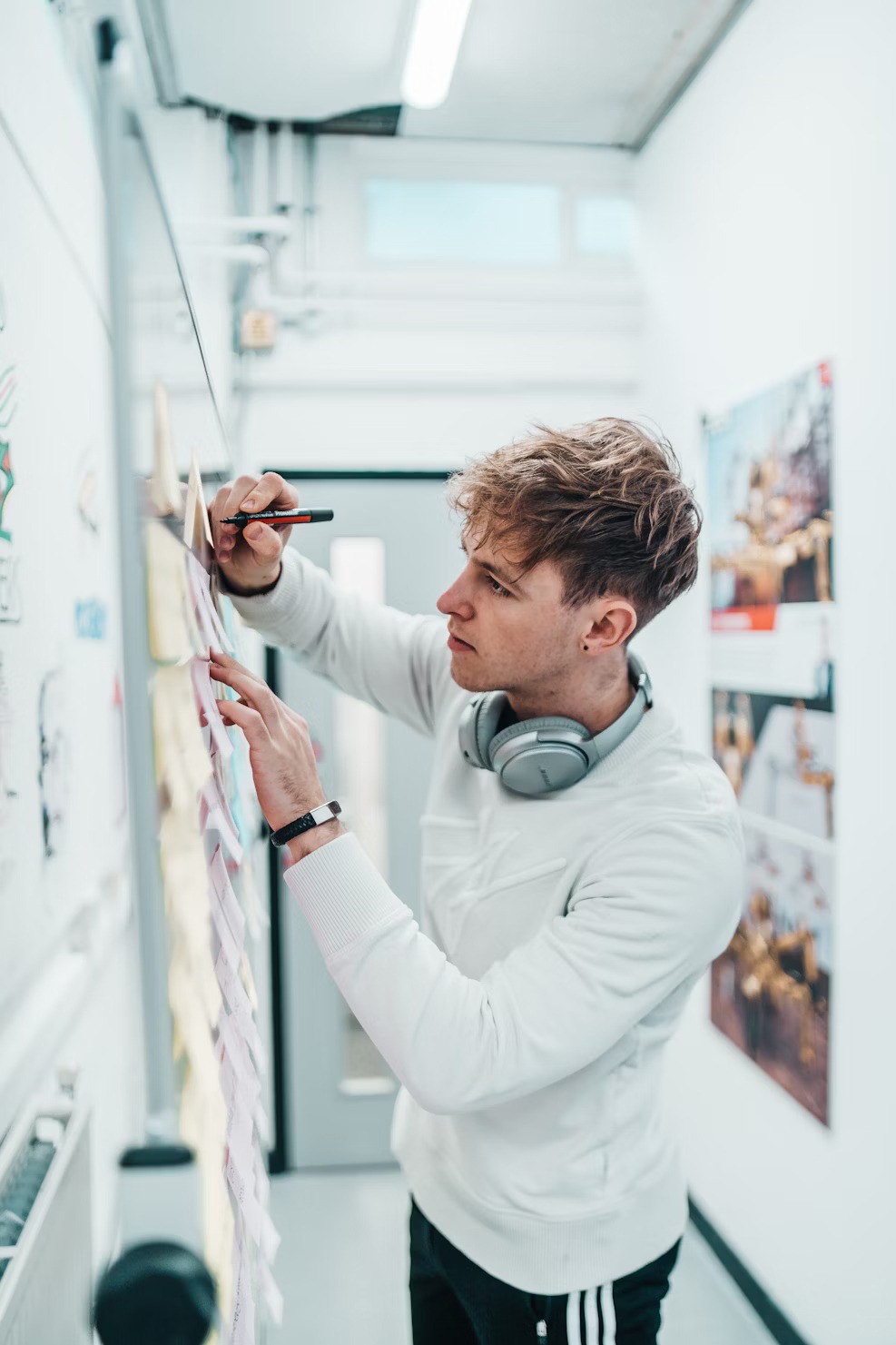 Stock image- man writing on whiteboard covered in post its
